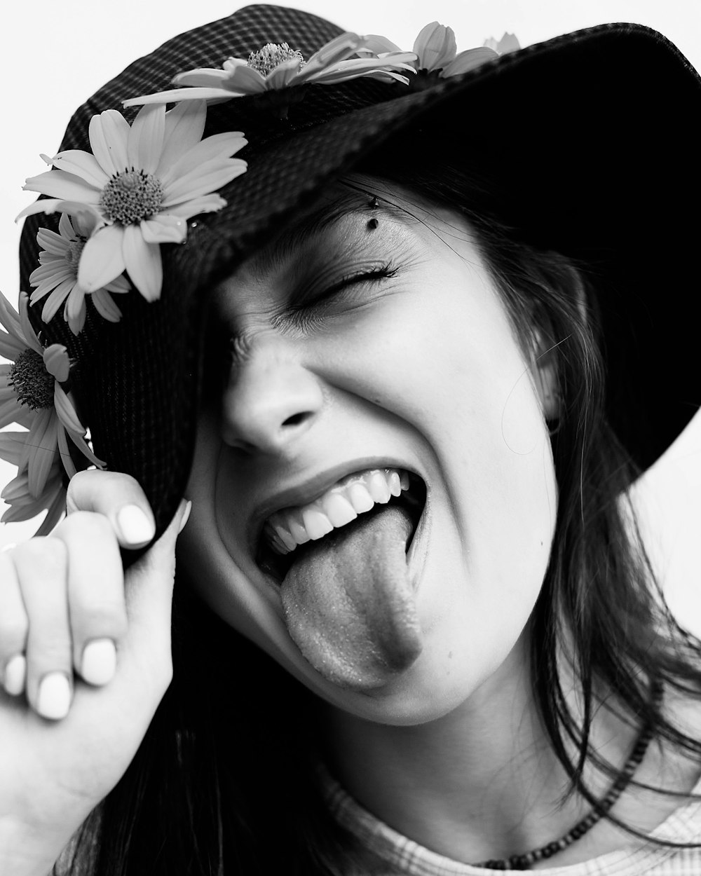 a woman wearing a hat and holding a flower in her mouth