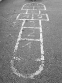A grainy photo of kids playing hopscotch on a cracked sidewalk in the 1980s.