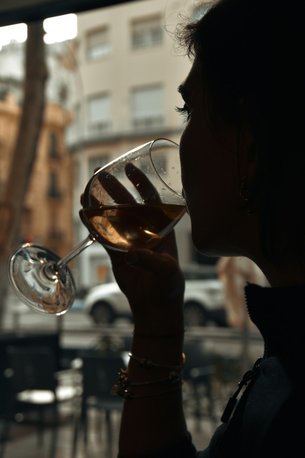 窓の前でグラスワインを飲む女性