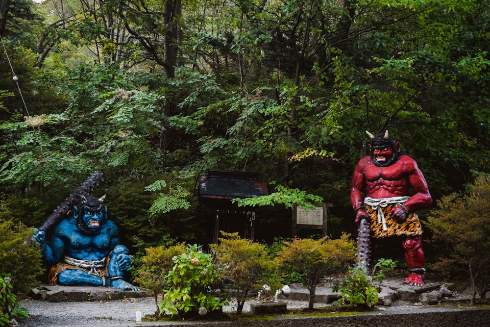 a couple of statues sitting in the middle of a forest
