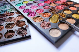 A vibrant makeup display featuring various shades and textures with slightly worn packaging.
