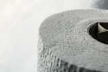 A close-up view of a roll of textured toilet paper, highlighting the details of its surface and the circular cardboard center.
