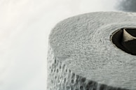 A close-up view of a roll of textured toilet paper, highlighting the details of its surface and the circular cardboard center.