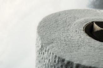A close-up view of a roll of textured toilet paper, highlighting the details of its surface and the circular cardboard center.