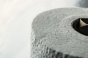 A close-up view of a roll of textured toilet paper, highlighting the details of its surface and the circular cardboard center.