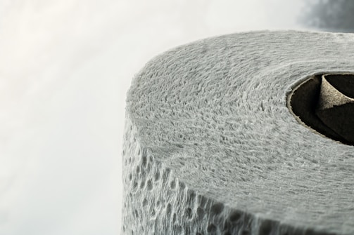 A close-up view of a roll of textured toilet paper, highlighting the details of its surface and the circular cardboard center.