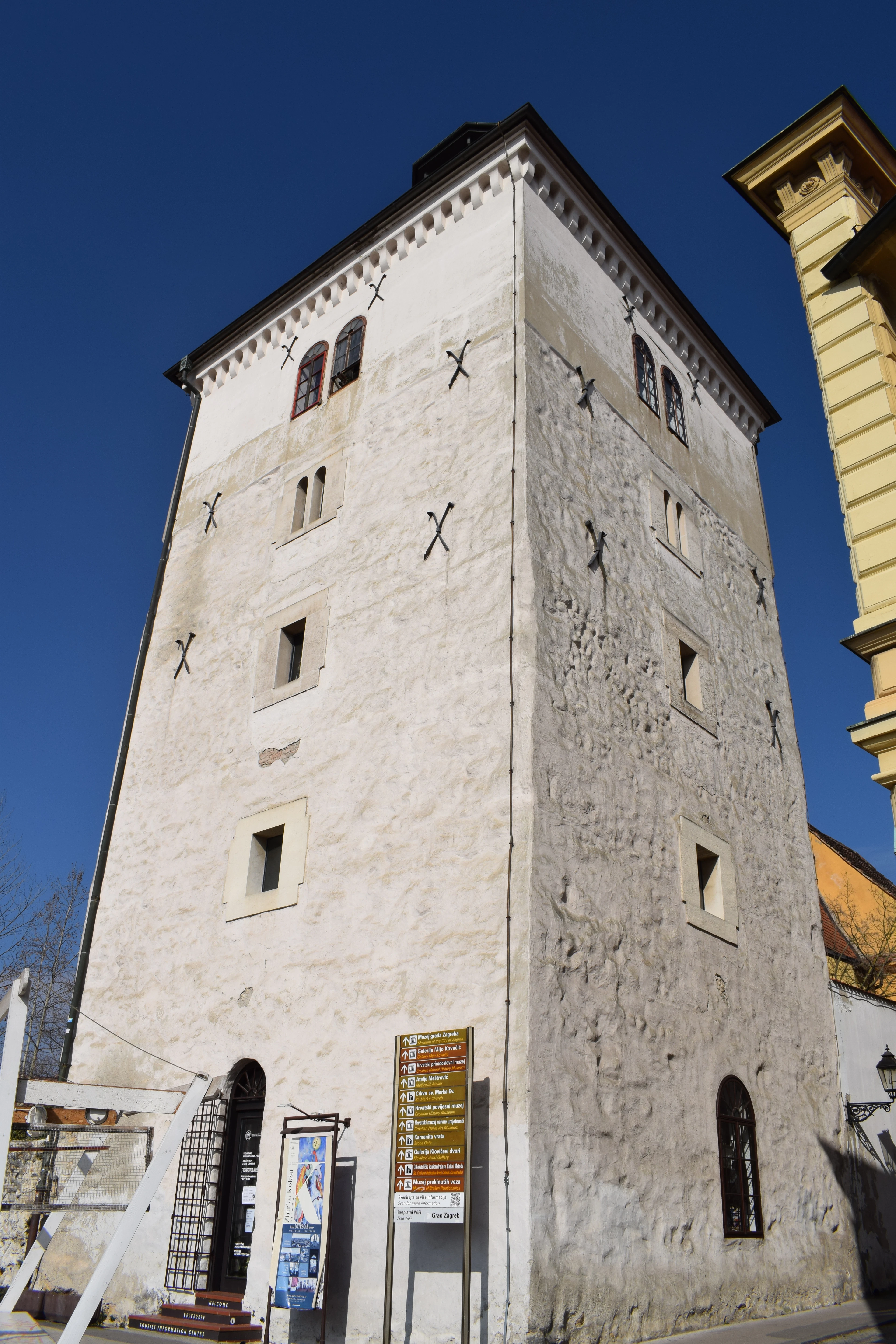 Lotrscak Tower's pale stone facade rises against a clear deep blue sky, its small arched windows catching the sun.