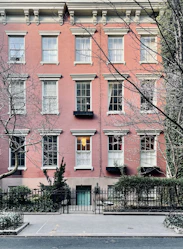 Elegant townhouse with brick facade and small garden in front.