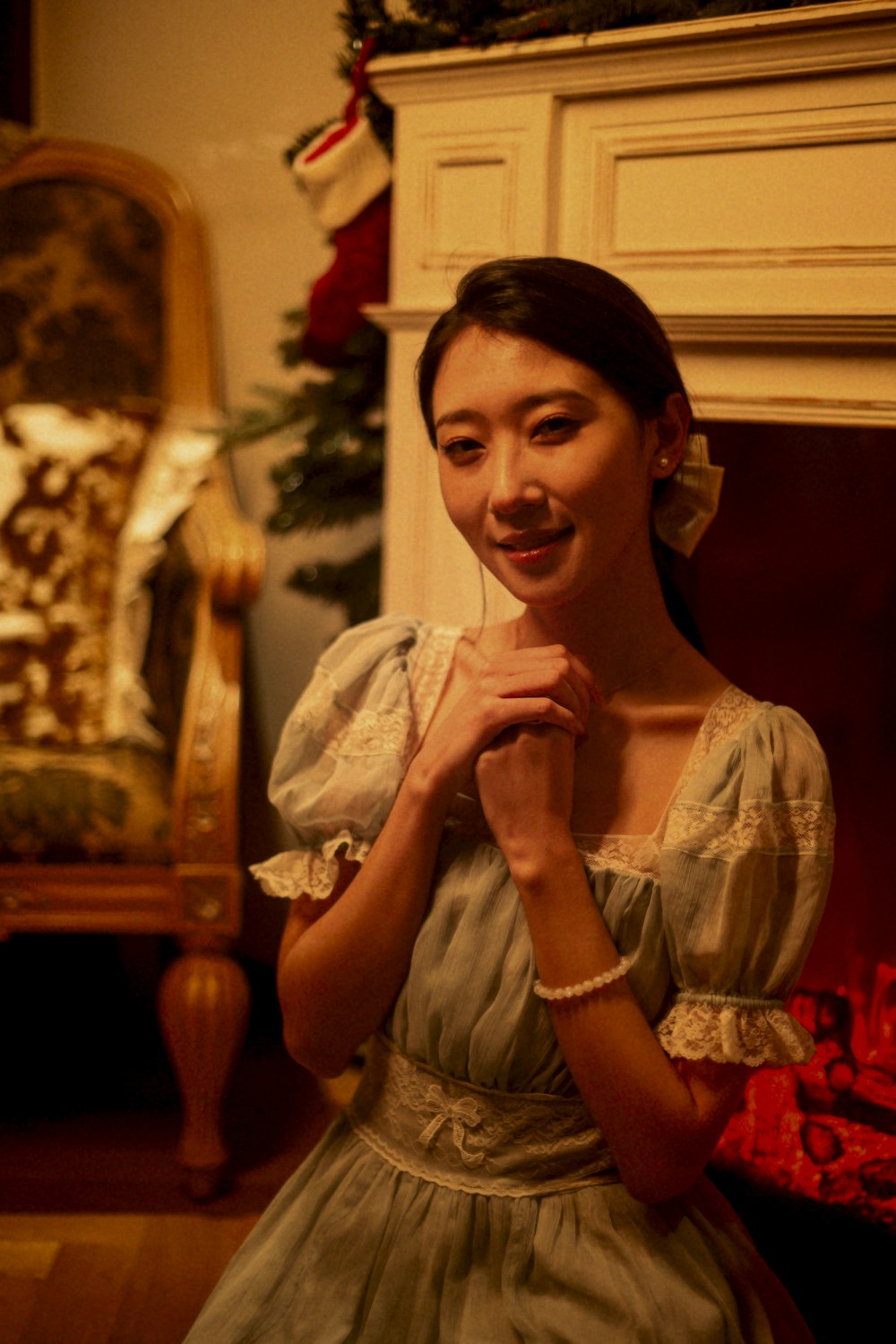 a woman in a dress standing in front of a fireplace