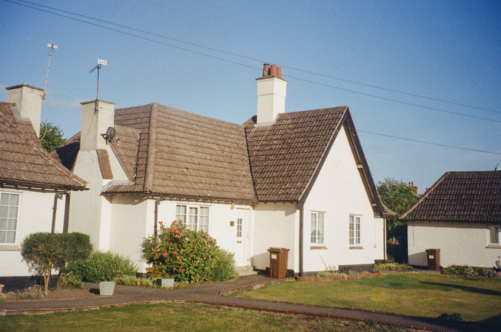 a white house with a brown roof and chimneys