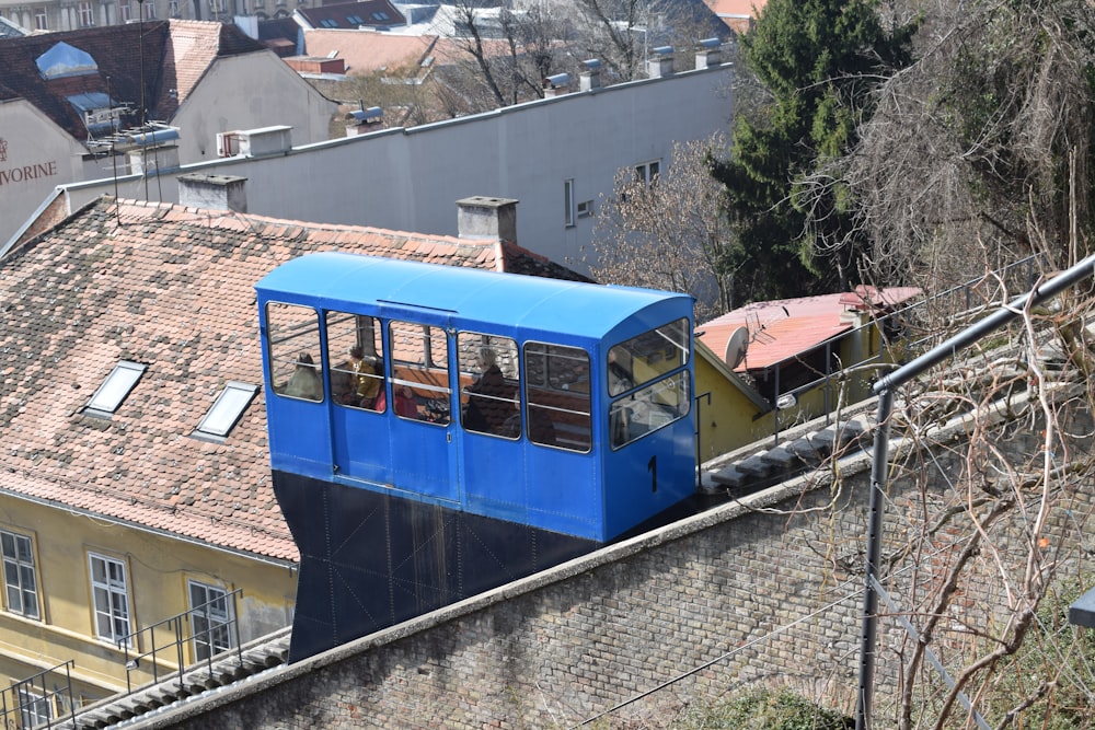 a blue train traveling down tracks next to tall buildings