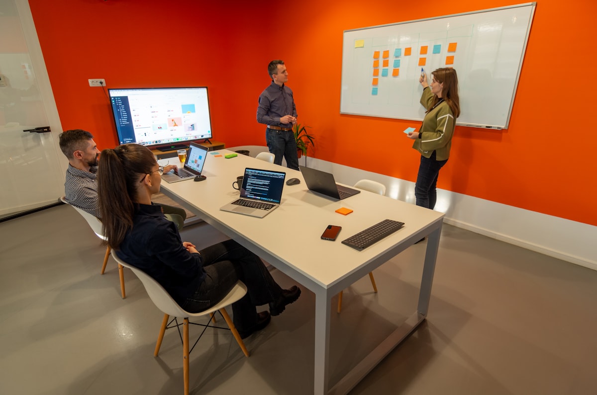 Meetingraum: Team plant Inhalte mit Laptops und Sticky Notes an einem Whiteboard