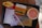 A fast-food meal on a black tray includes a box of Big Mac, a container of fries, a soft drink cup with a lid and straw, two condiment packets, a napkin, and a receipt. The Big Mac packaging is orange with sesame seed illustrations and Arabic script. The fries are in a red container, and the drink appears to be light orange in color.