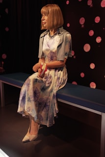 A lifelike sex doll seated elegantly in a softly lit room, highlighting its detailed craftsmanship.