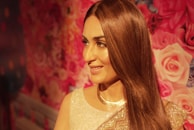 A model wearing a modern pastel dress paired with subtle gold jewelry, smiling softly.