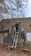 A group of people painting a mural of a forest on an outdoor wall.