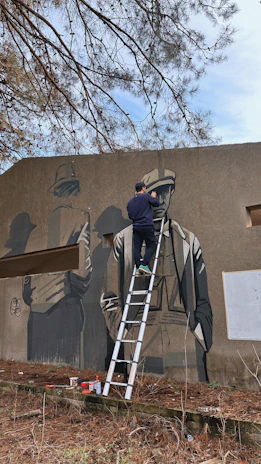 A local artist painting a mural on a city wall with onlookers admiring.