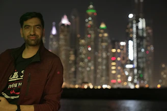 A young traveler smiling while holding a J1 visa document in front of an American cityscape.