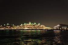 Night view of the hotel exterior illuminated with deep emerald green lighting reflecting the brand colors.
