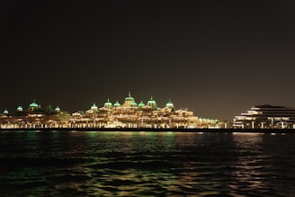 A nighttime view of the resort’s illuminated facade reflecting over calm water.