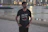 Man in casual clothes standing outdoors with city skyline in the background.