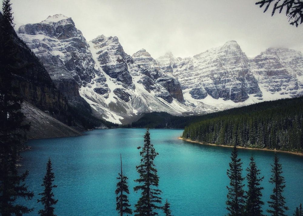 a blue lake surrounded by snow covered mountains