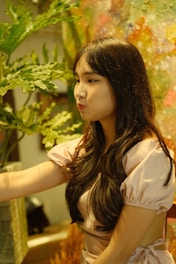 A woman gently massaging her scalp surrounded by green plants