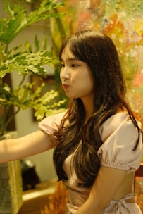 A woman gently massaging her scalp surrounded by green plants