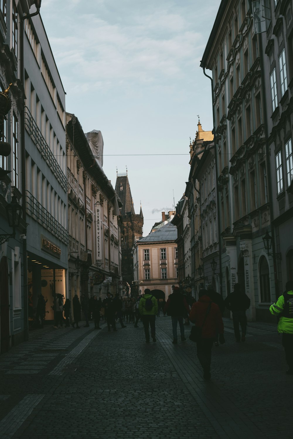 a group of people walking down a street next to tall buildings