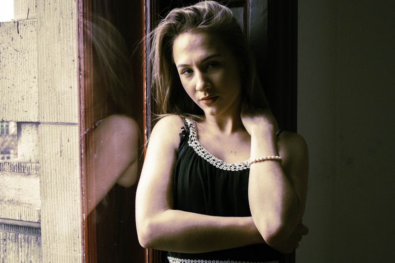 Elegant woman with crossed arms by window