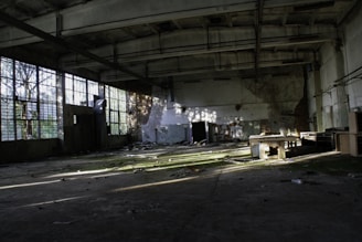 An empty industrial hall bathed in soft natural light, highlighting the silence of abandoned spaces.