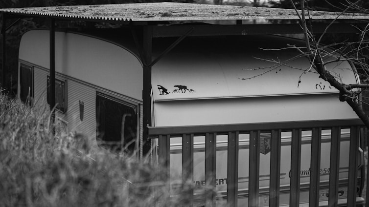 Photo of Mr Jim and Wrong Way Wendy standing beside their off-road caravan in the Australian outback.