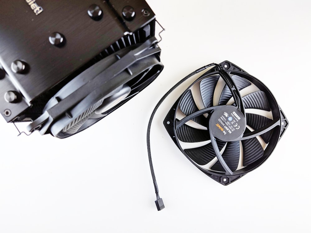 a black fan and a white fan on a white surface