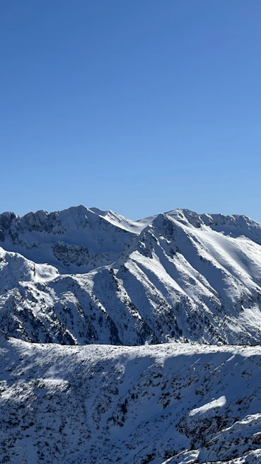 Snow-capped mountains of Central Asia under a clear blue sky at sunrise.