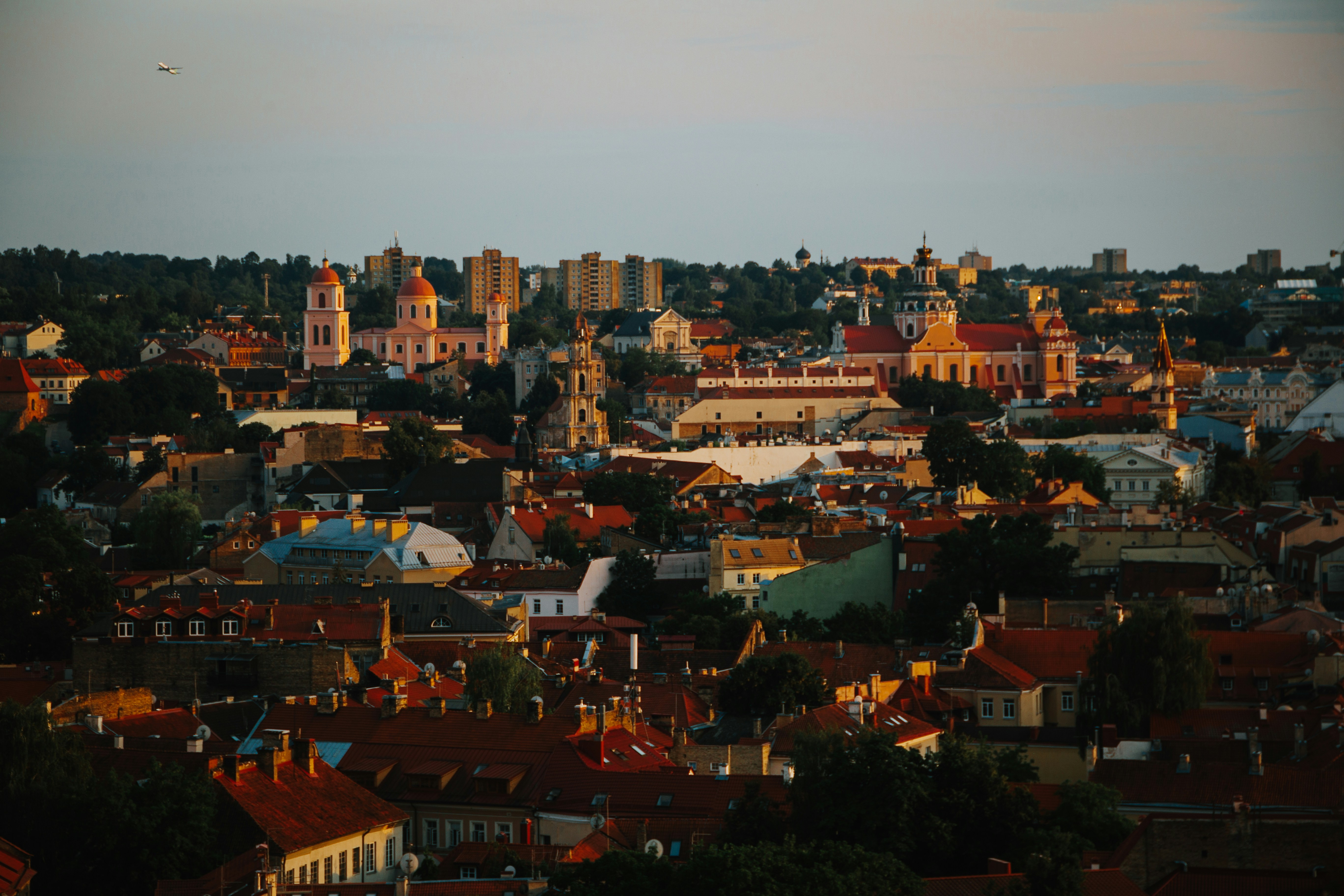 a view of a city with a plane flying in the sky