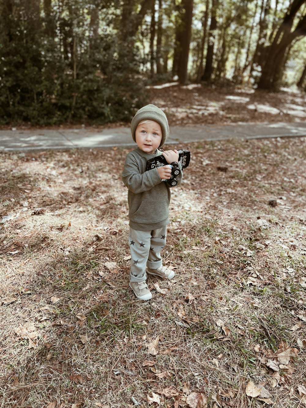 a young boy holding a camera in a wooded area