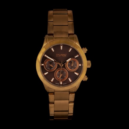 A luxurious gold wristwatch featuring a brown dial with three subdials and a gold metal bracelet. The watch has a sophisticated design with gold accents on the dial and three small control buttons on the side.