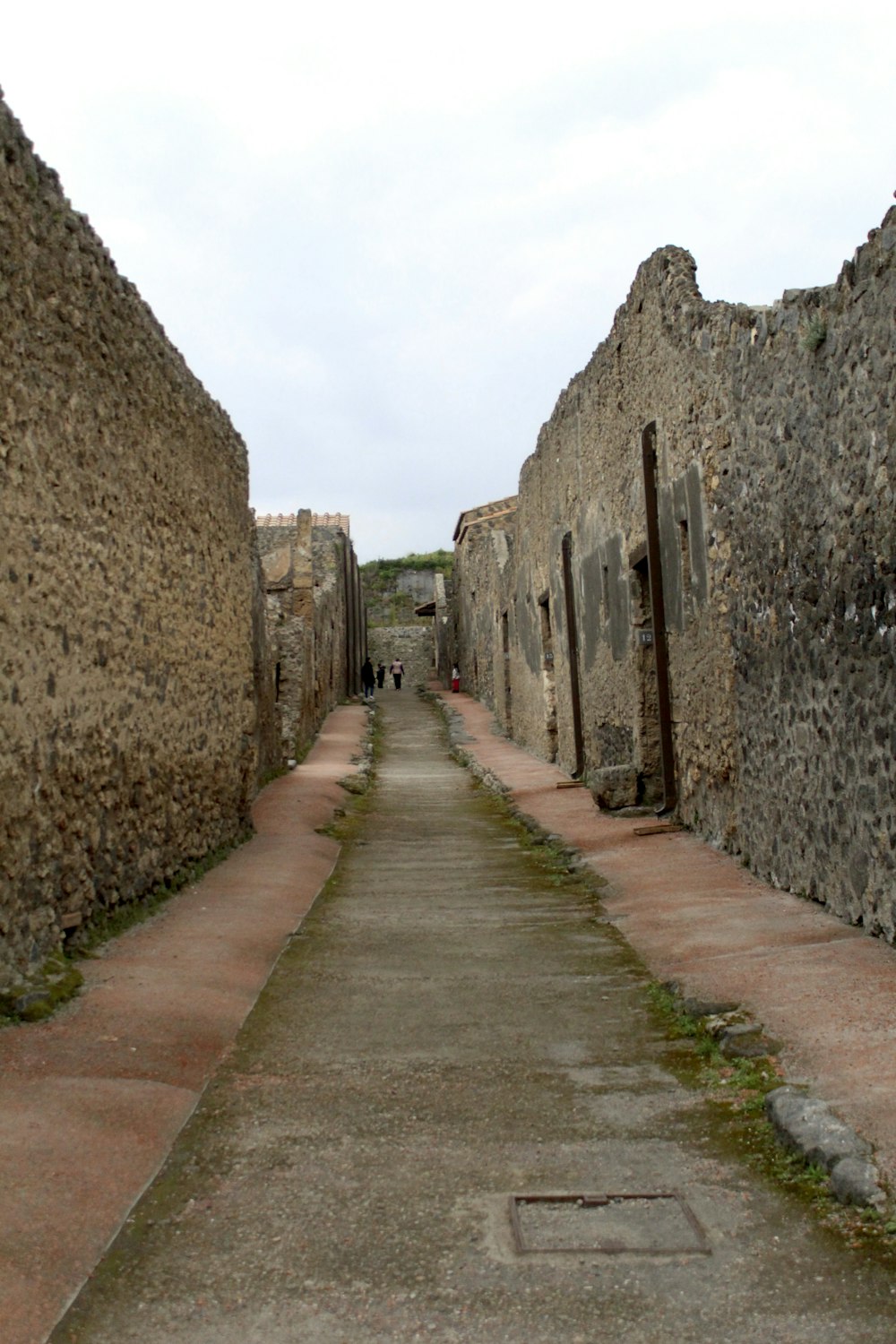 a narrow alley way with a stone building in the background