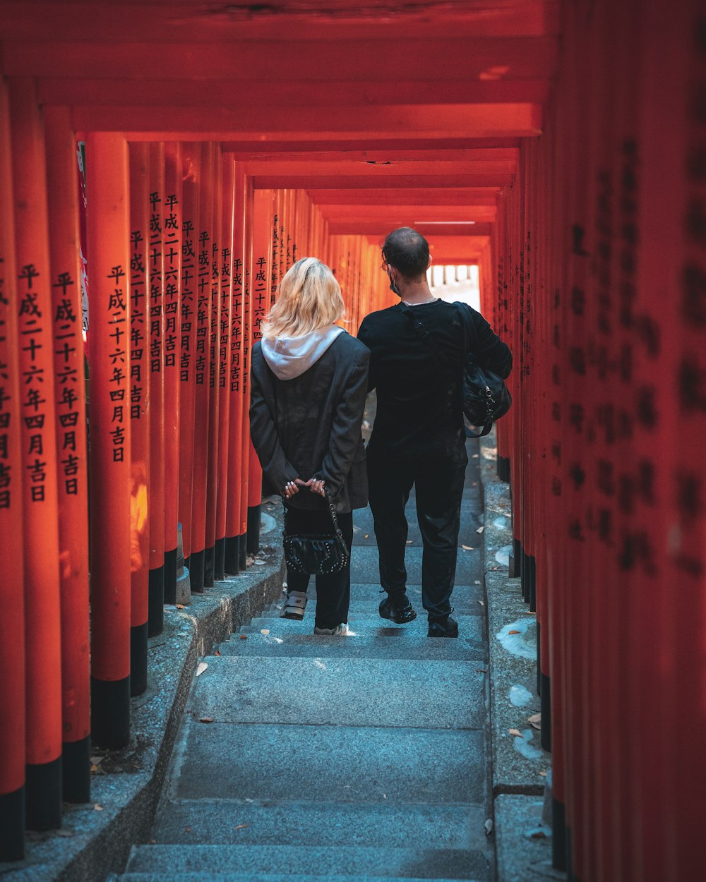 a man and a woman walking through a tunnel of red tori tori tori tori tori