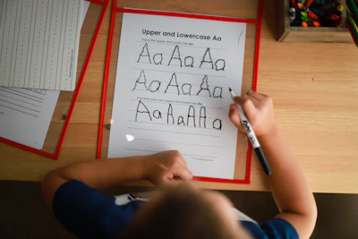 Close-up of tiny hands tracing letters on a pastel-colored printable sheet.