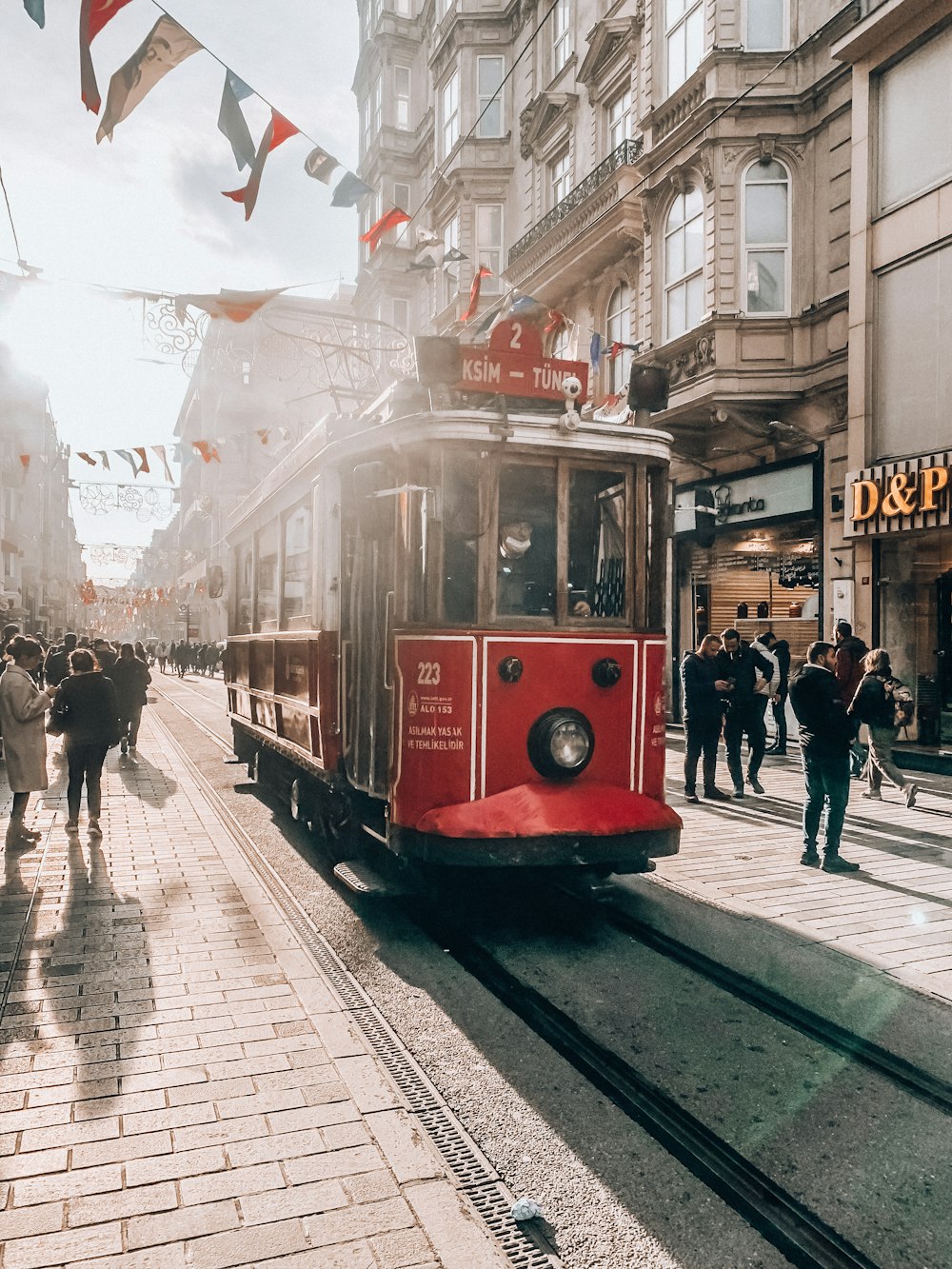 a red trolley car traveling down a street next to tall buildings