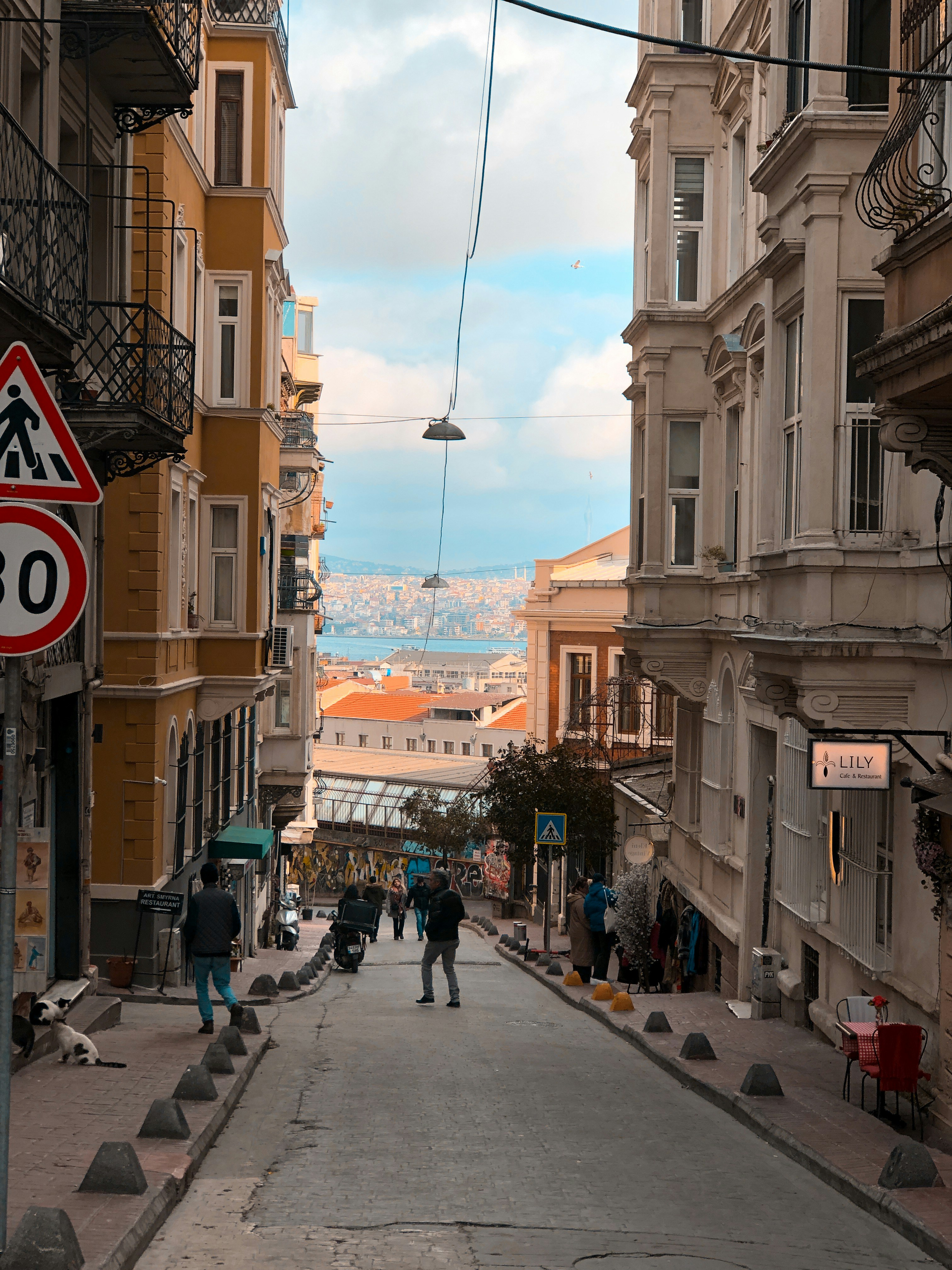 A narrow city street with people walking down it