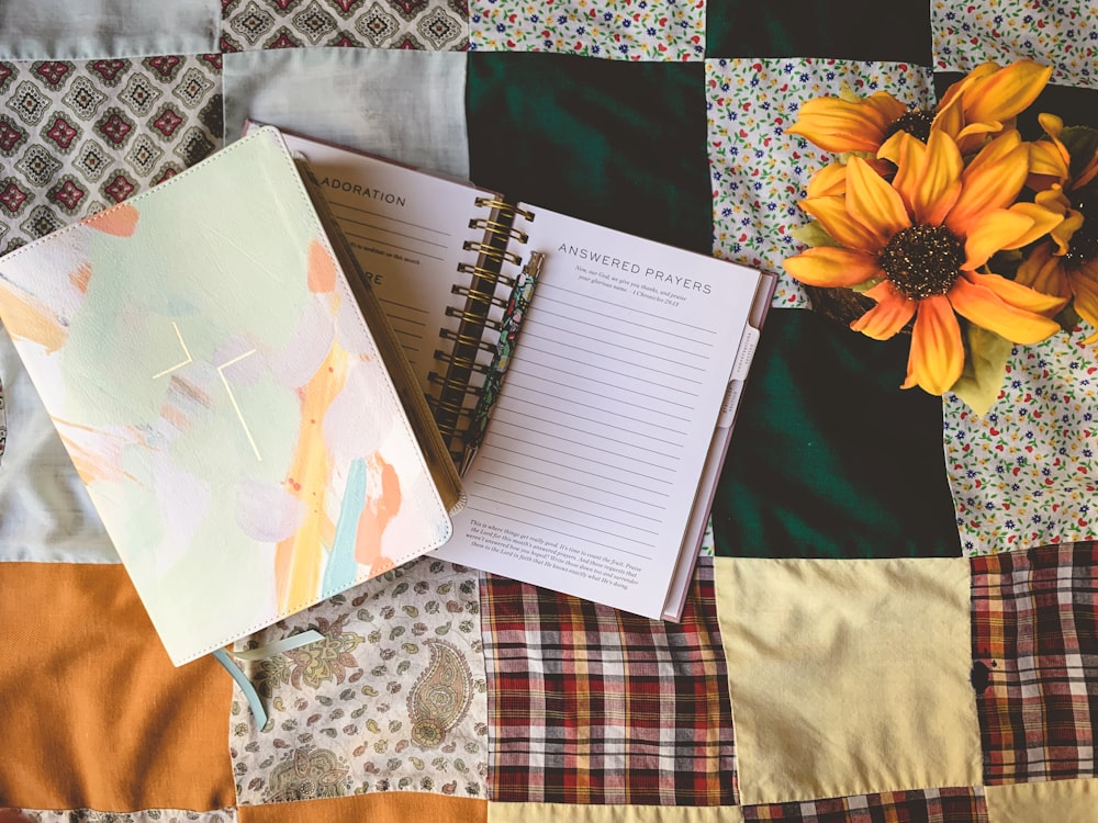 a notebook and a flower on a quilt