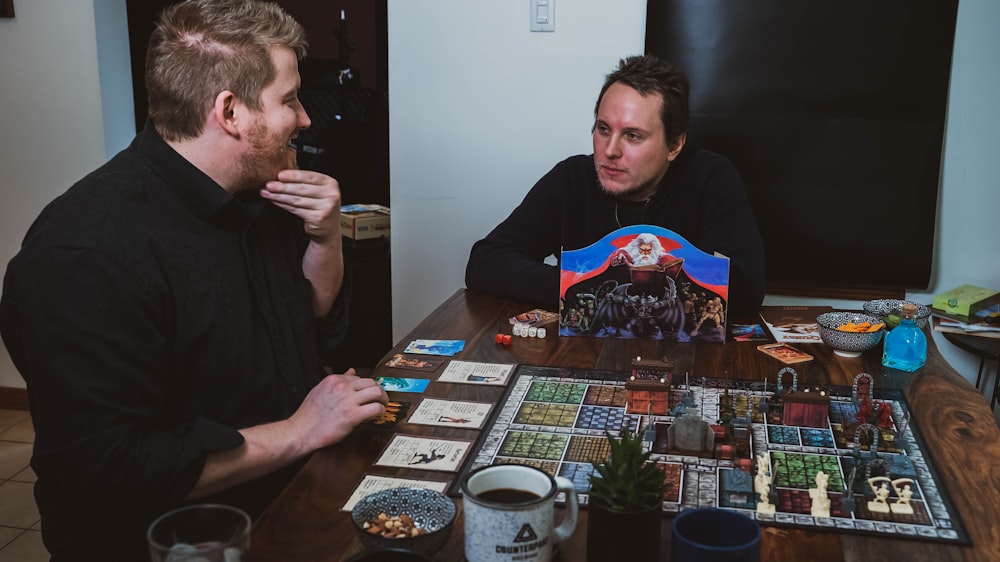 two men sitting at a table with a board game