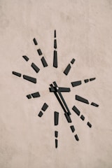 An elegant clock on a textured wall with minimalist decor.