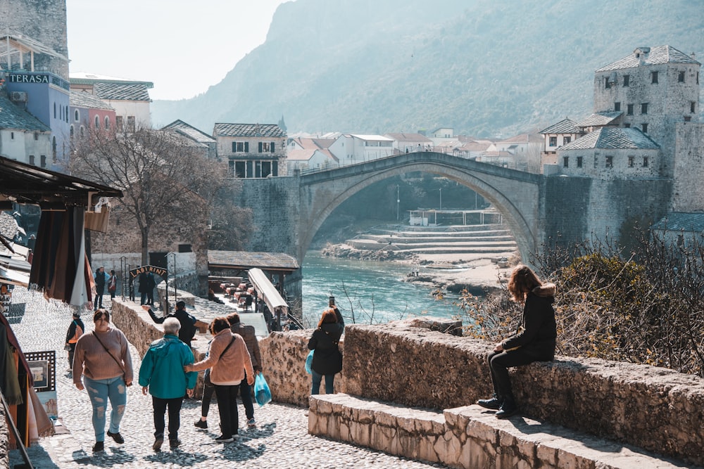 a group of people walking along a stone bridge