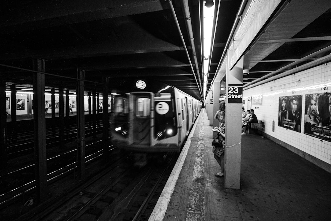 a black and white photo of a subway train, New York Metro Train E is arriving at 23 street