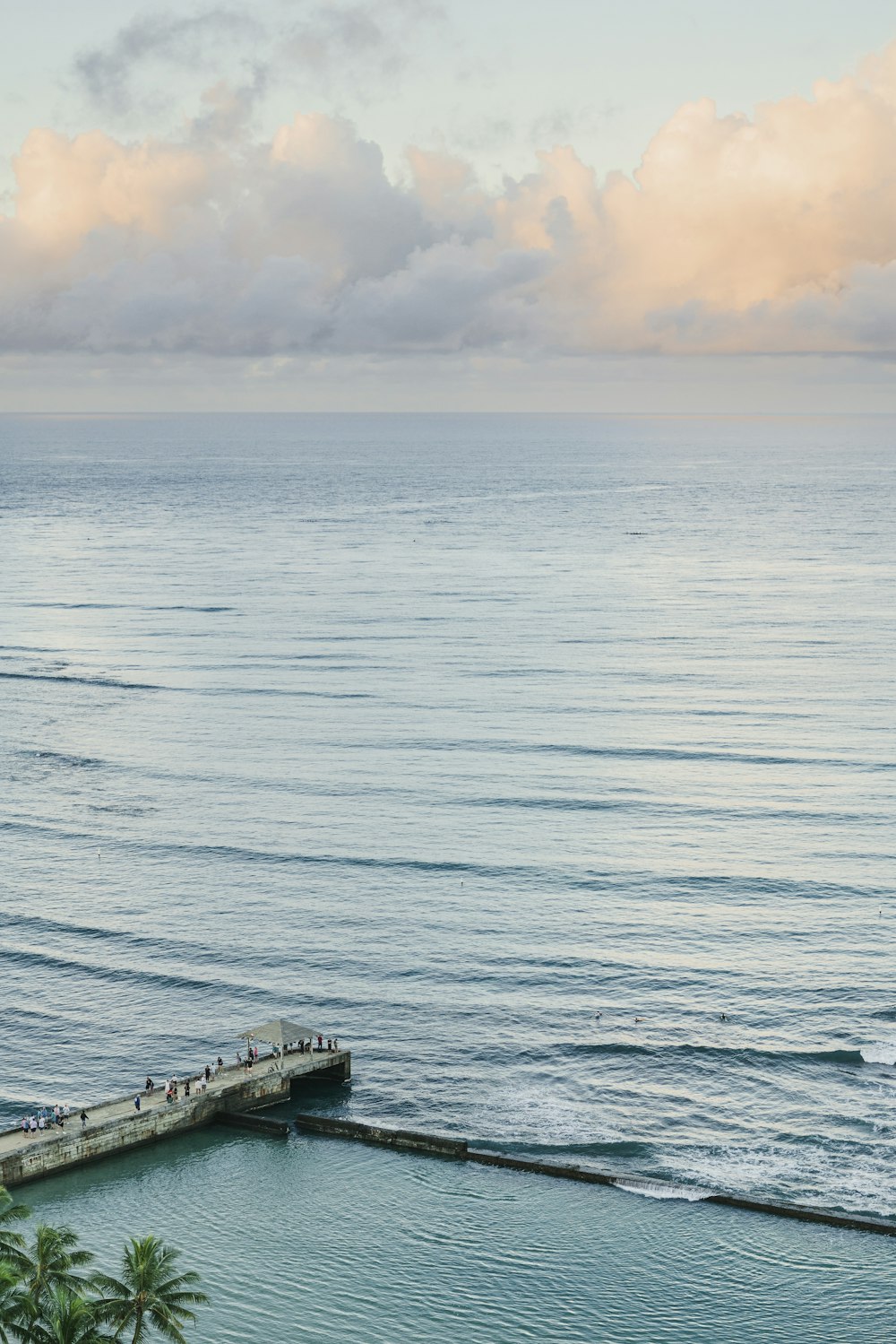 a group of people standing on a pier next to the ocean