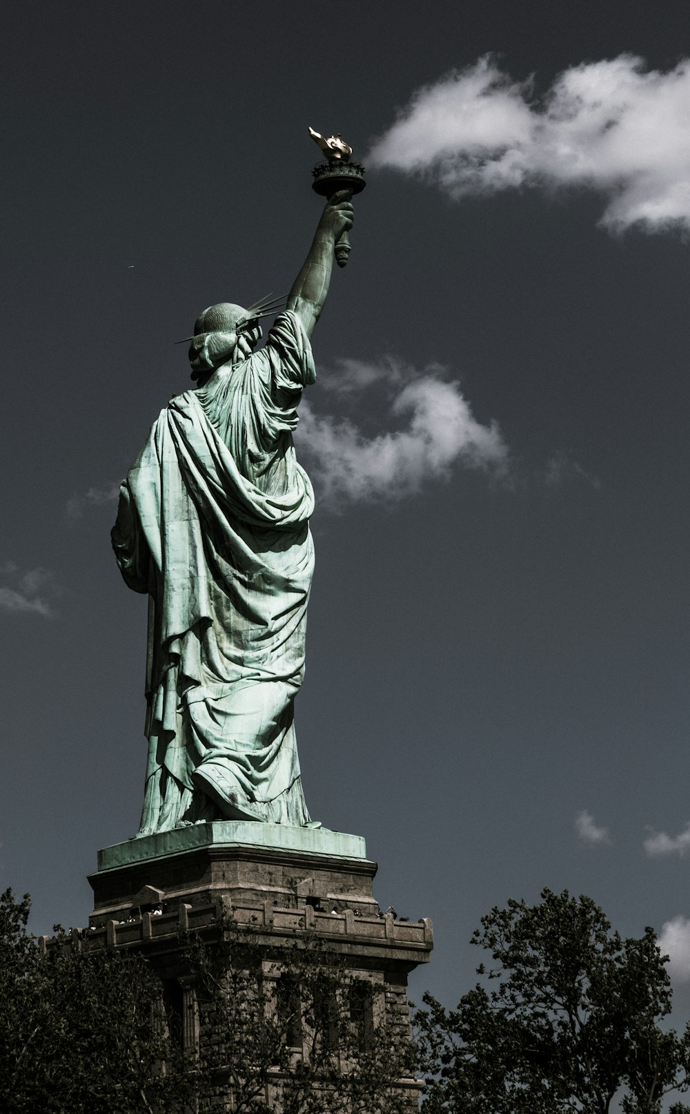 a statue of liberty is shown against a cloudy sky