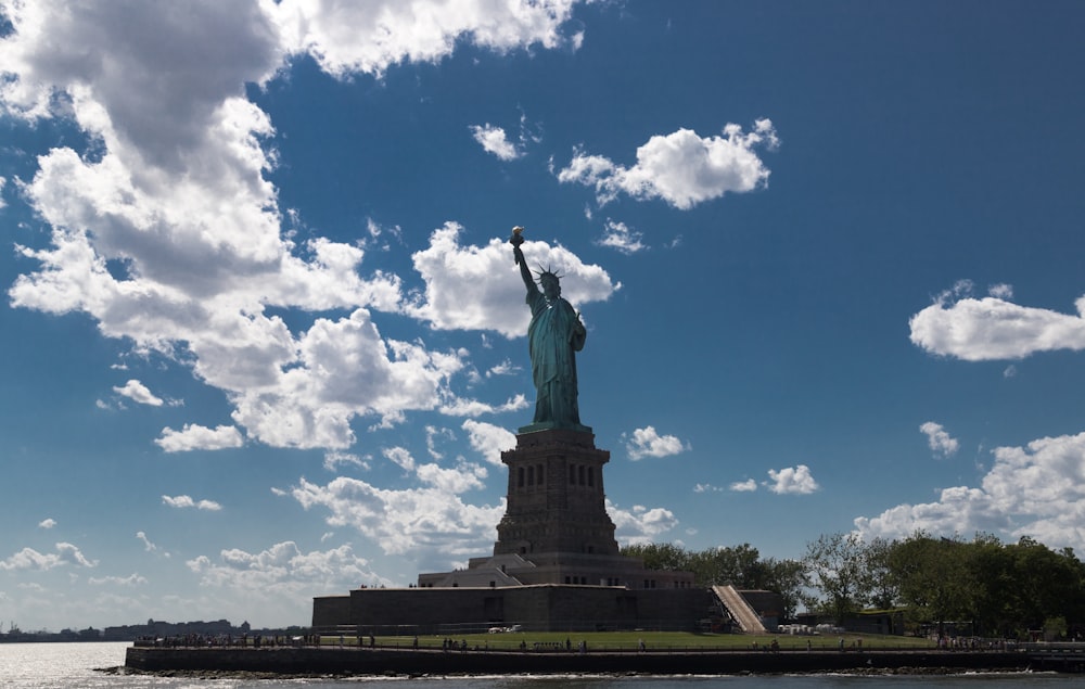 the statue of liberty stands in the middle of a body of water